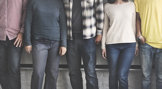 Photo image of five people dressed in different casual apparel standing side-by-side.