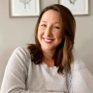 This is a portrait photo of Cristina Holt, Director of Project Management at WebDevStudios. She is sitting at a desk, smiling at the camera, and has her head resting on her left hand.