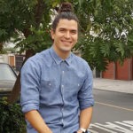 A photograph of Daniel Lama, Project Manager at WebDevStudios. Daniel is outdoors, sitting on a car and smiling a the camera.