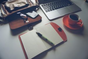 This is a photo of an open journal, open laptop, and a cup of coffee.