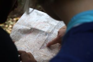 A photography of two people looking at a map with one person pointing a spot on the map.