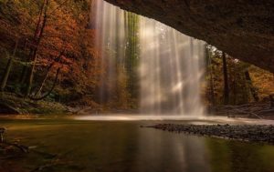 This is an outdoor photo of a waterfall taken from behind the waterfall.