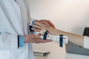 This is a photograph of a person in a white lab coat, probably a doctor, placing a thumb split onto an anonymous person's hand.