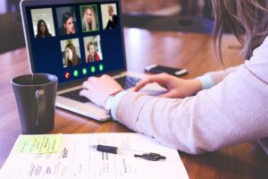 This is a photograph of a person on an open laptop having a video conference call.