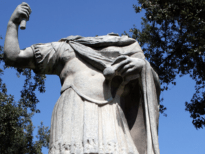 This is a headless statue during the daytime with a deep blue sky in the background.