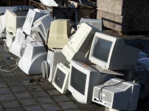 This is a photograph of a pile of old computers sitting outside.